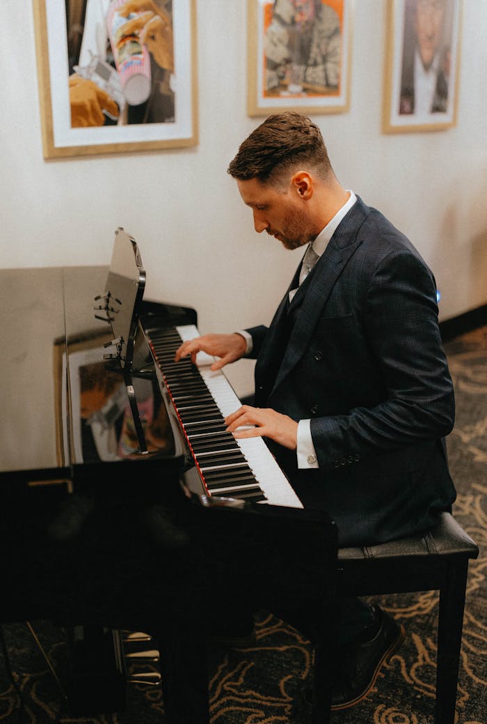 why-choose-us Man in a suit elegantly playing a grand piano indoors, side view.